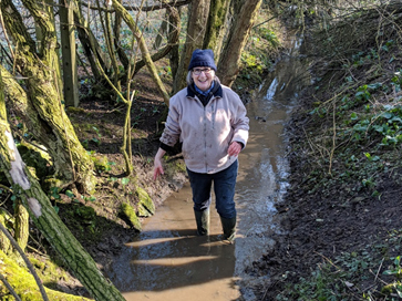 a woman standing in a muddy river smiling
